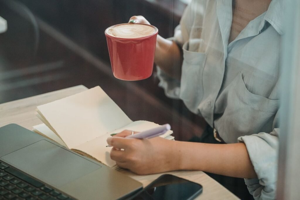 Woman with coffee writing in a notebook, a daily journaling habit