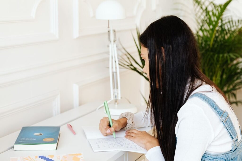 Student writing in a notebook at her desk