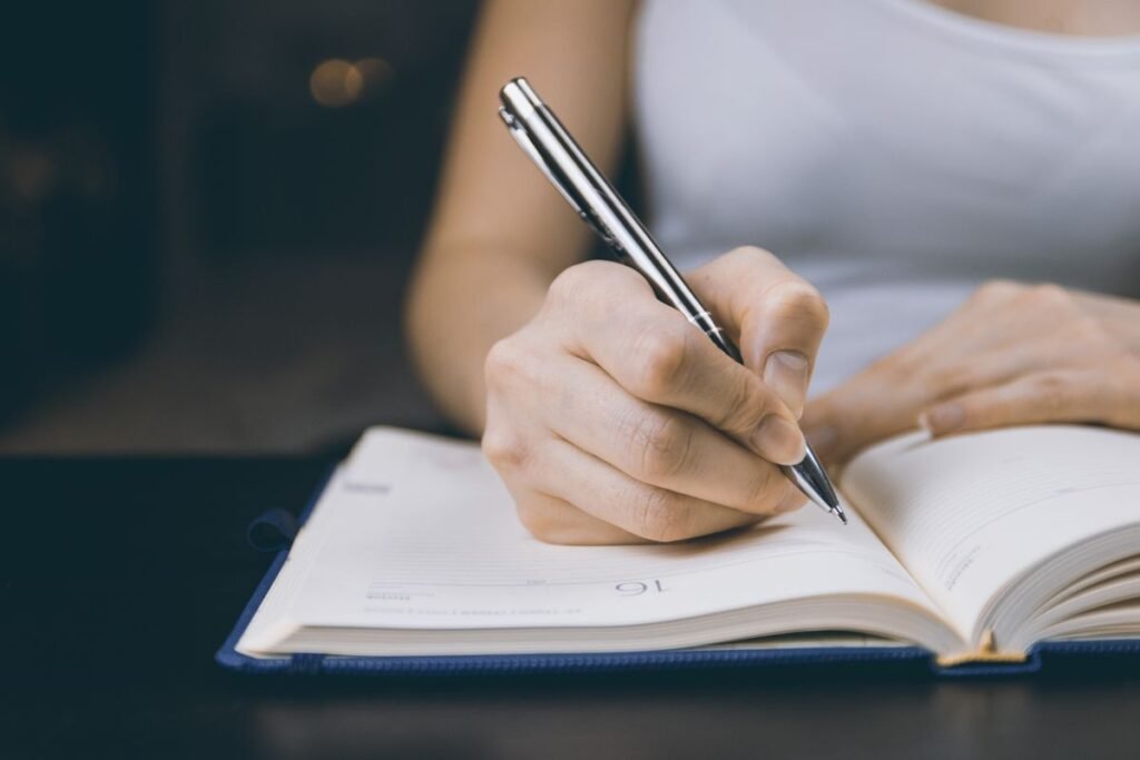 Person writing in a notebook to start a journal