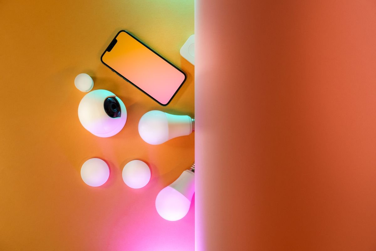 Top view of a smartphone and camera styled on a soft pastel background