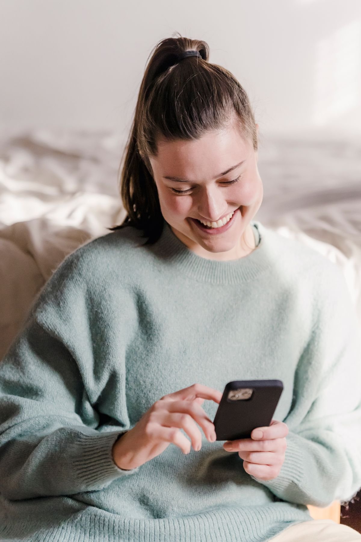 Smiling woman casually using her mobile phone at home