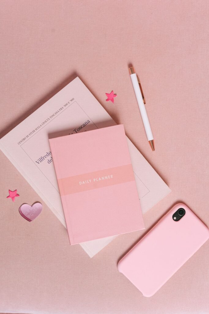 Aesthetic pastel pink flatlay with a planner and smartphone