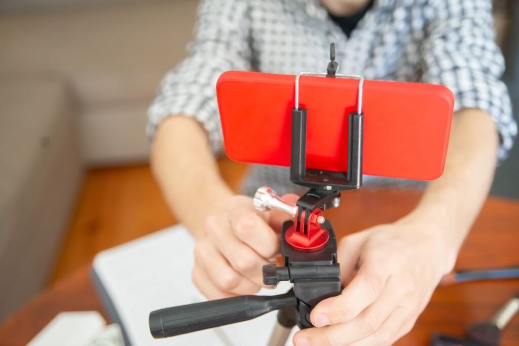 Person holding a smartphone mounted on a tripod, representing setting up for a live stream