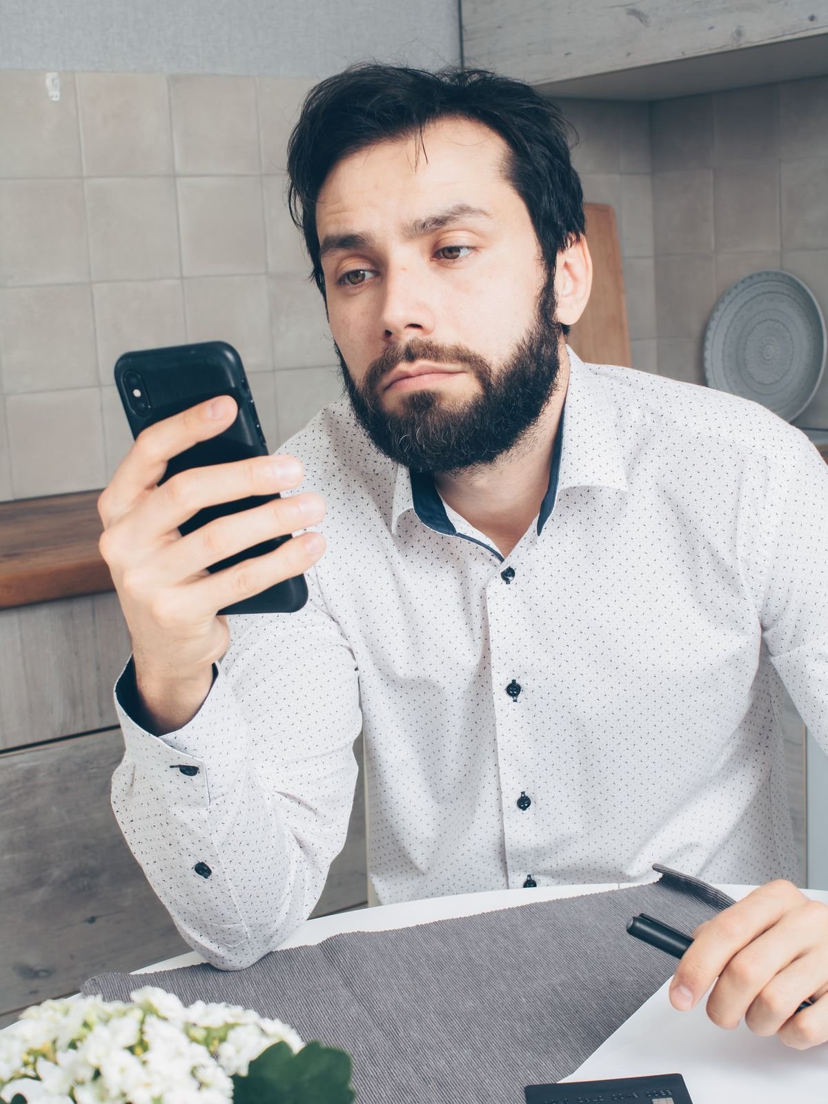 Man looking frustrated while checking his smartphone, representing being unable to reach someone online