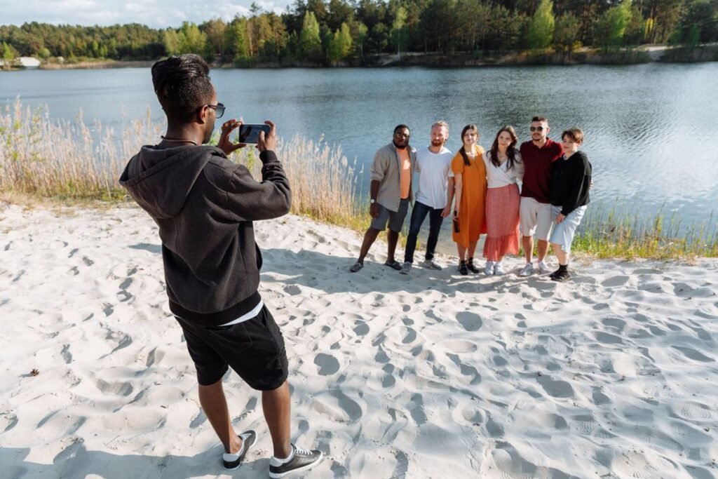 Person taking a photo of a group of friends near a lake