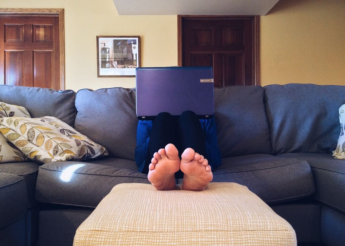 Person relaxing on a couch streaming content on a laptop in a casual home setting