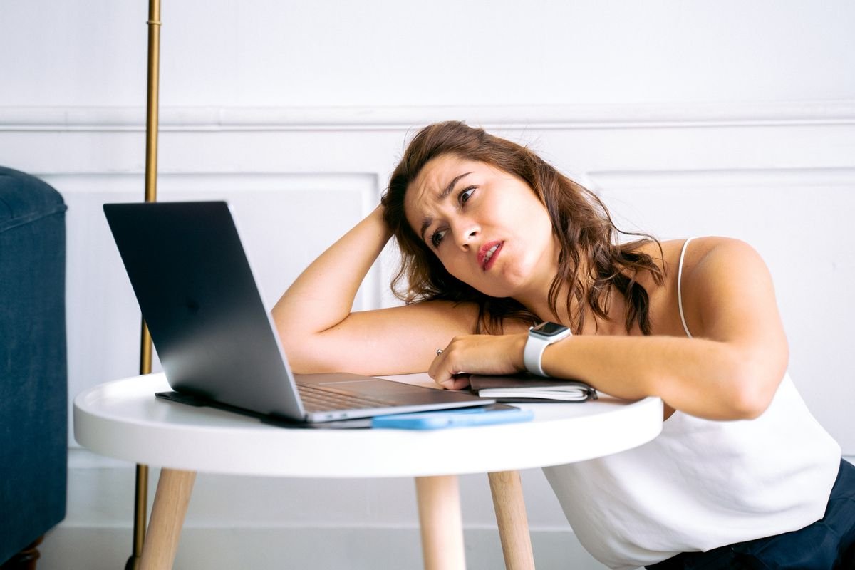 Woman leaning back with a wary, concerned expression while looking at her laptop