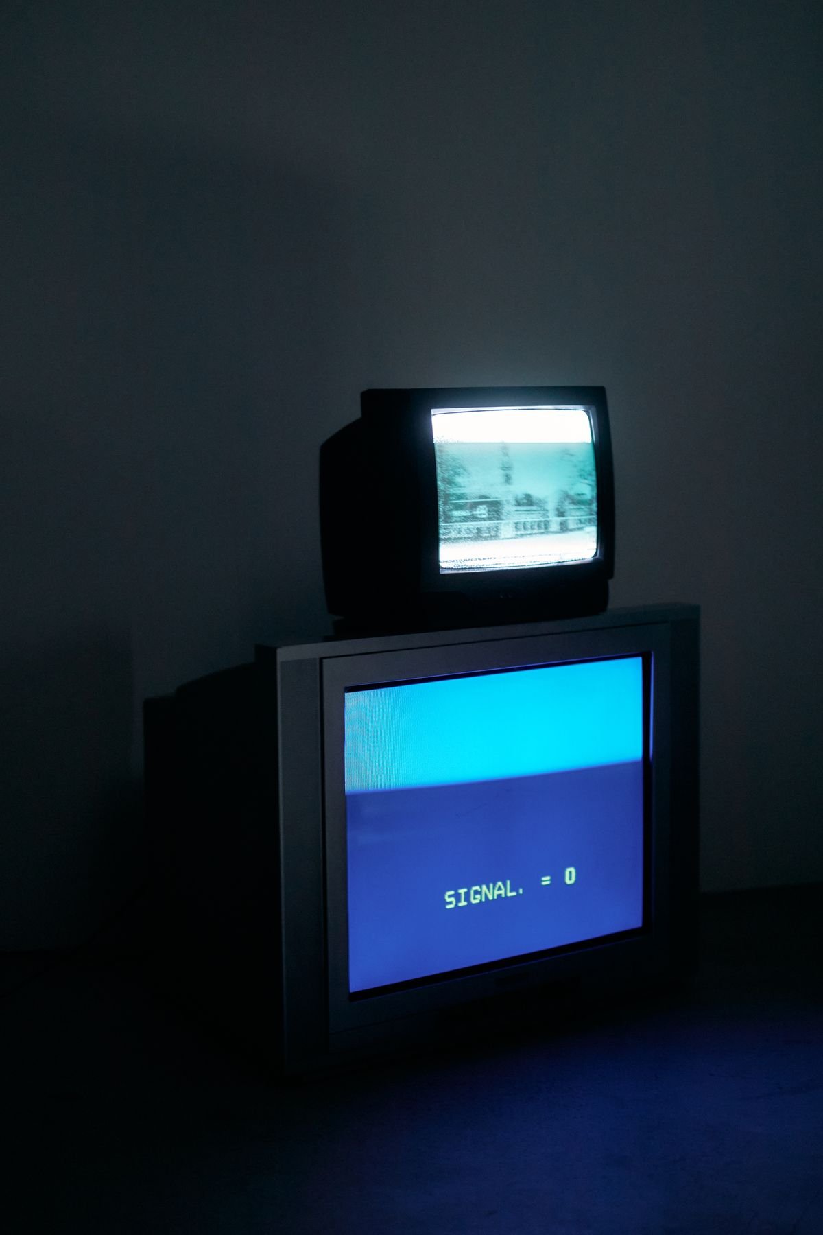 Retro televisions glowing in a dark, moody room