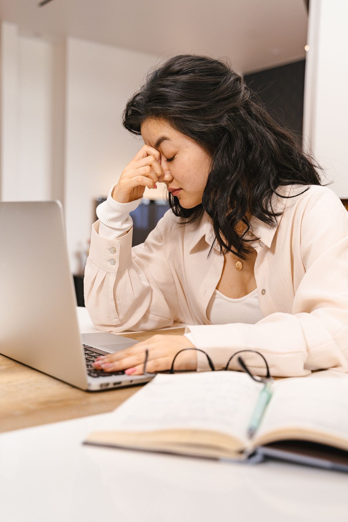 Frustrated woman rubbing her forehead while looking at a laptop screen